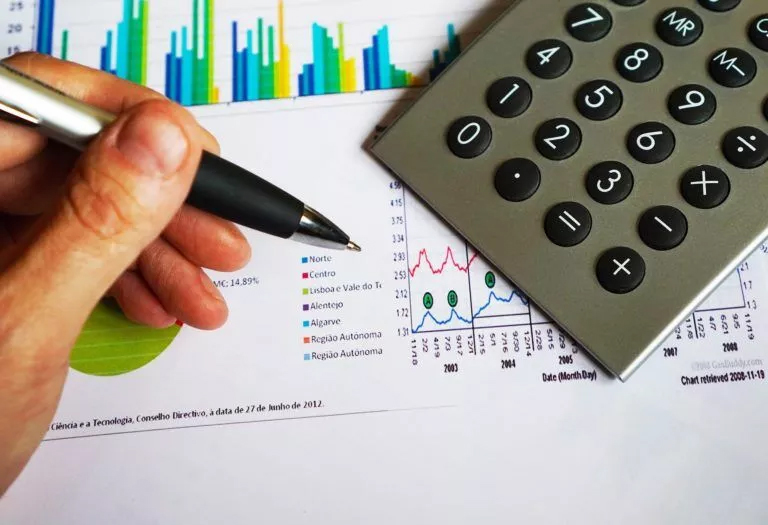 Accounting Homework Help: Seeking Solutions with Pen and Calculator A student's hand holding a pen and calculator, seeking Accounting Homework Help