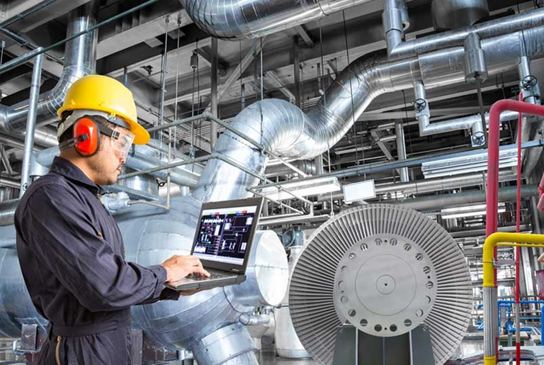 Engineering assignment and homework: Hard Hat, Laptop, and Learning A man in a hard hat and safety glasses using a laptop. An engineering student focused on homework and assignments.
