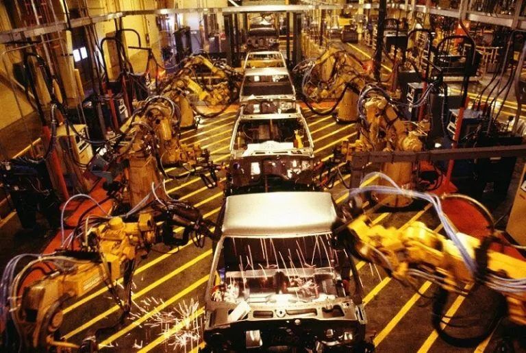 Efficiency in Motion: Automotive Assembly Line Engineering A factory with cars on the assembly line, showcasing an Industrial Engineering Tutors concept