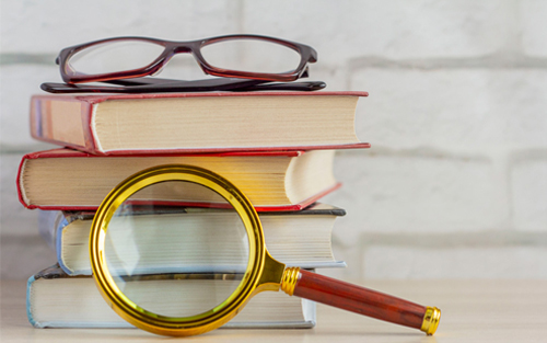 Literature Review Setup: Books, Glasses, and Magnifying Glass on Wooden Table Books, glasses, and magnifying glass on wooden table - perfect setup for a literature review concept